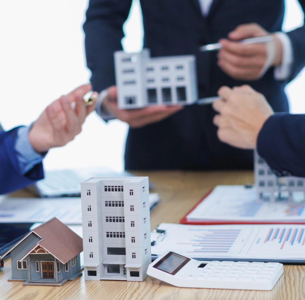 Real estate discussion with building models, documents.